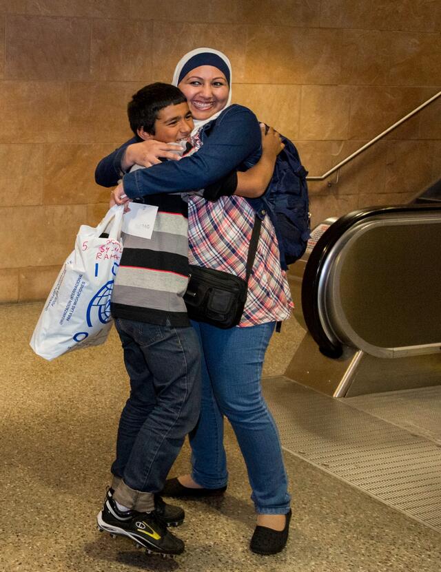 A refugee family hugs, smiling as they are reunited in a U.S. airport. 