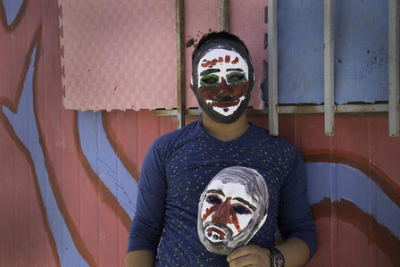 A Syrian boy wears a mask he painted at an IRC self-expression workshop for young refugees A young Syrian refugee wears and carries masks he painted at an IRC workshop