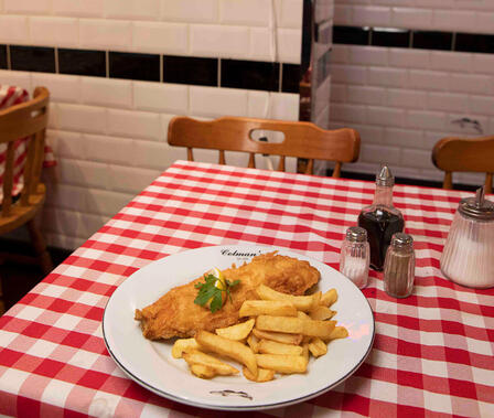 A plate of fish and chips on a table at a fish and chip shop in England