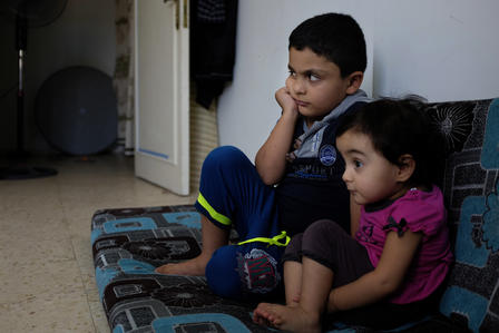Hisham watches cartoons with his little sister Two Syrian children watch cartoons