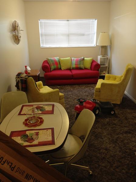 A furnished apartment ready for a newly arriving refugee family set up by volunteers from the First Unitarian Church. Apartment setup with dining table, chairs, couch, and sitting area.