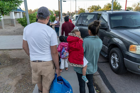 A family approaches a car with their belongings for transport to their next destination