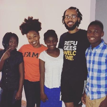 IRC volunteer, Yennifer Castillo, and IRC AmeriCorps VISTA member, Chase Beasley, with Congolese students. A man and a woman in their twenties, pose for a picture with three middle and high school age students in their home.