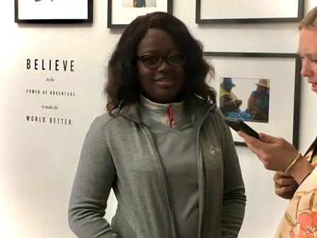 Fatima attends an entrepreneur workshop at Cotopaxi A woman looking at her pone, and another looking at the camera with hands in her pocket.