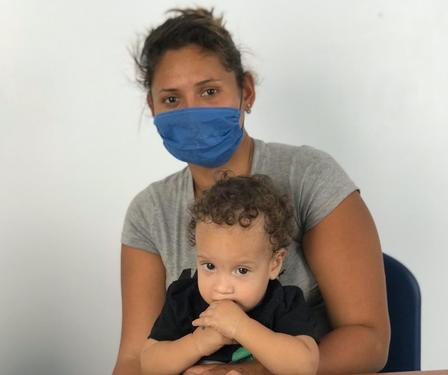 A woman wearing a mask sits with her child on her lap at an IRC-run clinic at the Simón Bolívar bridge. 