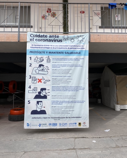 A banner promoting COVID-19 prevention at the IRC-supported "triage hotel" in Mexico. A banner in Spanish promoting COVID-19 prevention, hanging off of a second floor railing in an old motel that serves as an IRC-supported "triage hotel" in Mexico