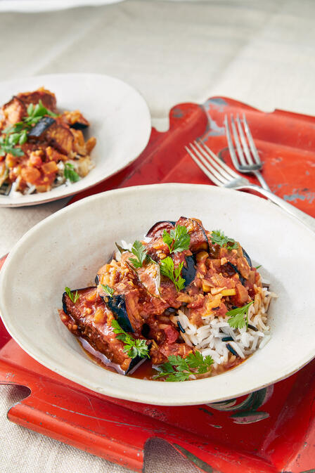 Chef Shanthini’s fried eggplant curry in a white dish on a red placemat. 