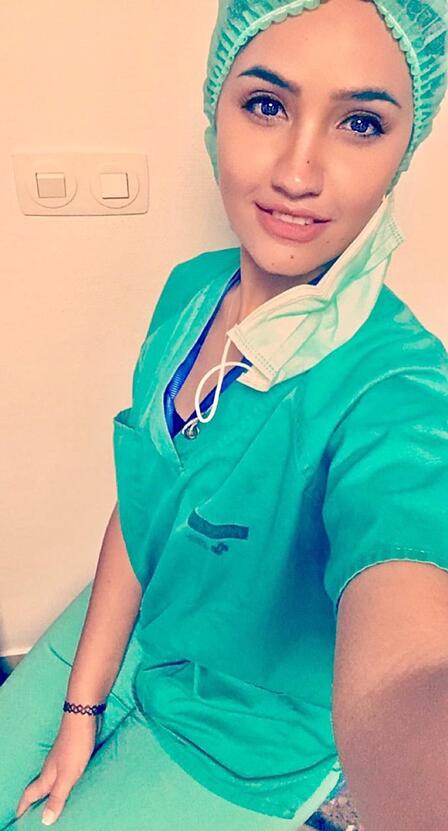 Dr. Rose M. Al-Nsour, wearing blue scrubs, smiles and takes a selfie photo