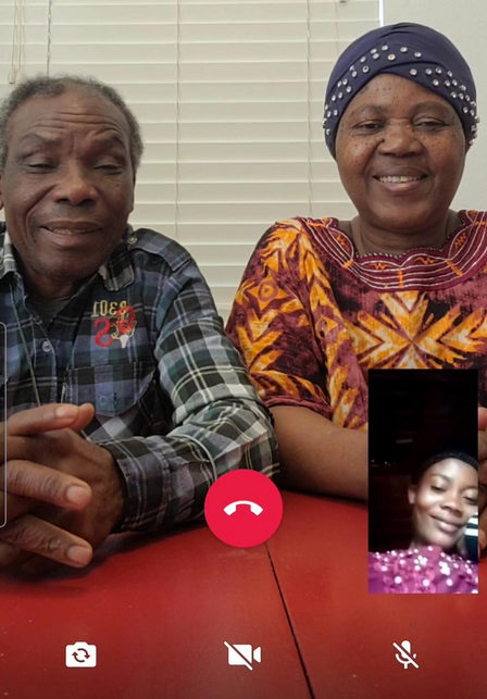 A screenshot of a smart phone, with Patrice and his wife sitting at a table and their daughter Mauwa in a small box on the lower right side of the screen