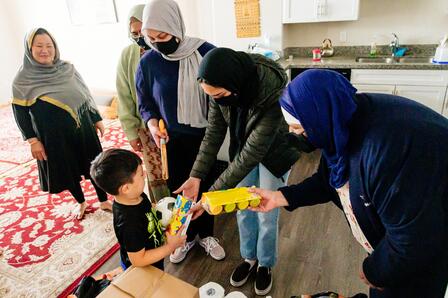 The Al-Mustafa Foundation delivers gifts Three women hand gifts to a young boy, with two other women smiling in the background.