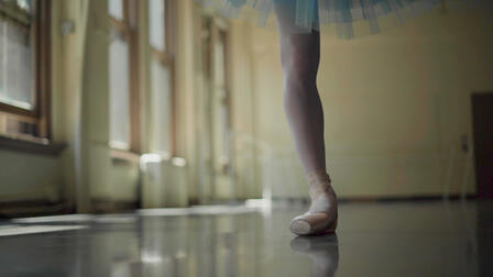 Ballerina Christine Shevchenko rehearses in a dance studio. A close-up of the ballerina's leg and point shoe while dancing