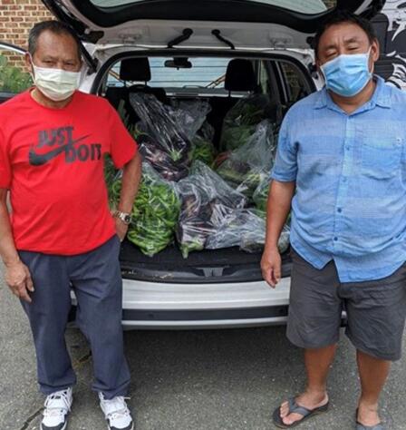 Two men stand in front of a vehicle packed with fresh produce Two men stand in front of a vehicle packed with fresh produce