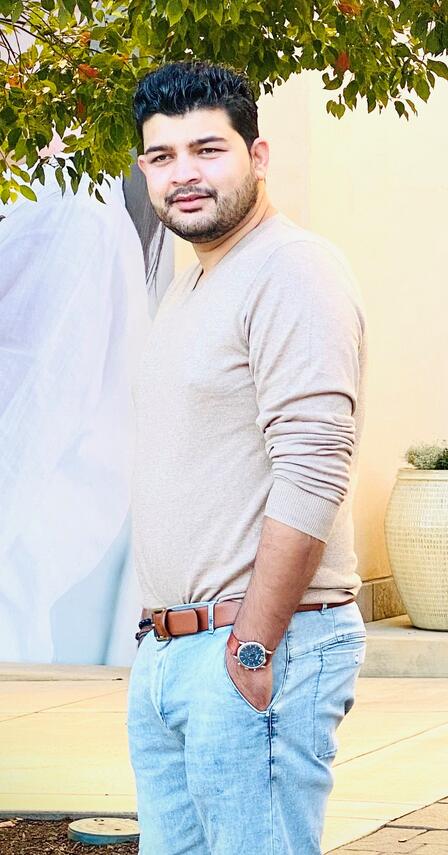 Ahmad stands outside with his hands in his pockets looking at the camera 