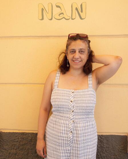 A woman stands against a wall that reads, "Nan."
