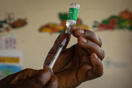 An IRC health worker in Uganda draws a dose of COVID-19 vaccine into a syringe
