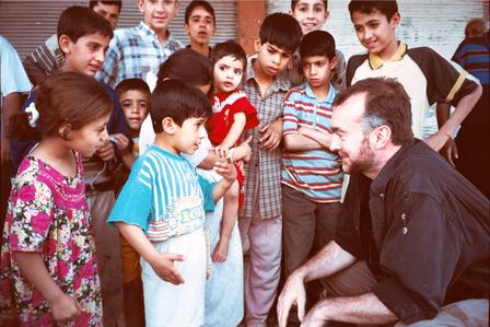 Michael Kocher in Iraq A middle aged man squats down as he talks with a group of Iraqi children.
