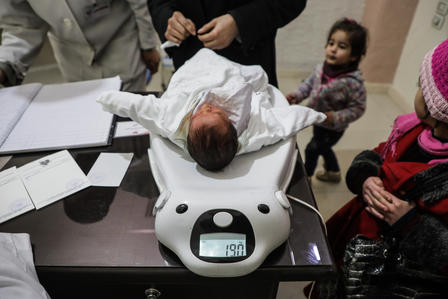 A doctor and nurse weigh a malnourished baby at an IRC-supported clinic in Eastern Ghouta run by a local partner. A doctor and nurse weigh a malnourished baby at an IRC-supported clinic in Eastern Ghouta run by a local partner.