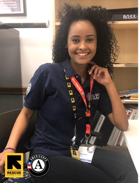 Hope Newman: IRC Career Readiness AmeriCorps VISTA Hope sits wearing her AmeriCorps shirt and IRC lanyard