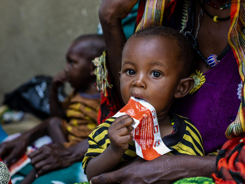 Ett barn äter en näringsrik klämmis för undernäring