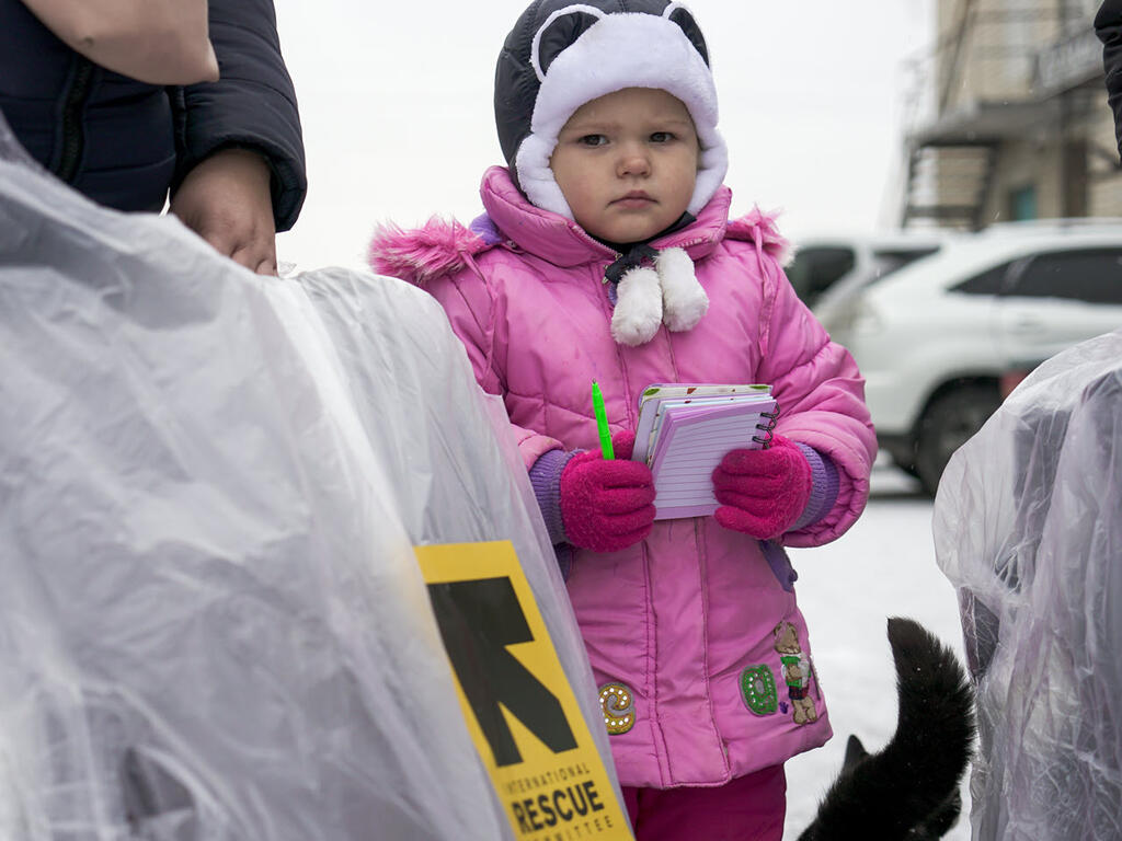 A child and her parents receive winter kits and register for financial aid in Kharkiv Oblast, Ukraine.