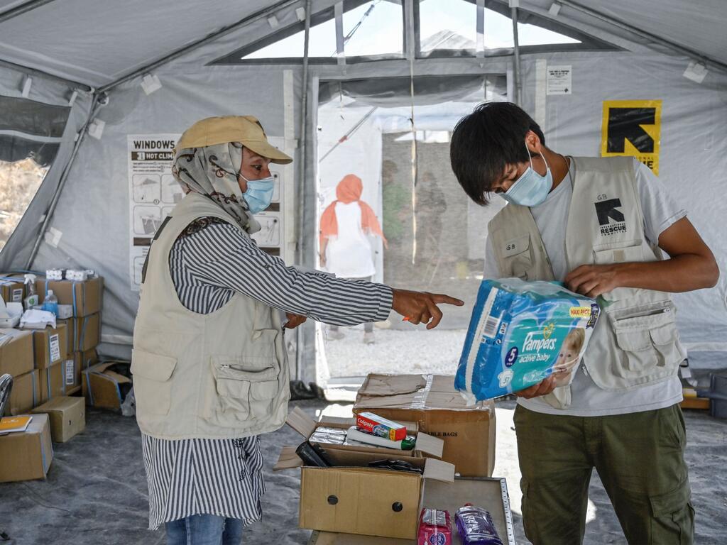 Two people sorting through supplies inside a tent