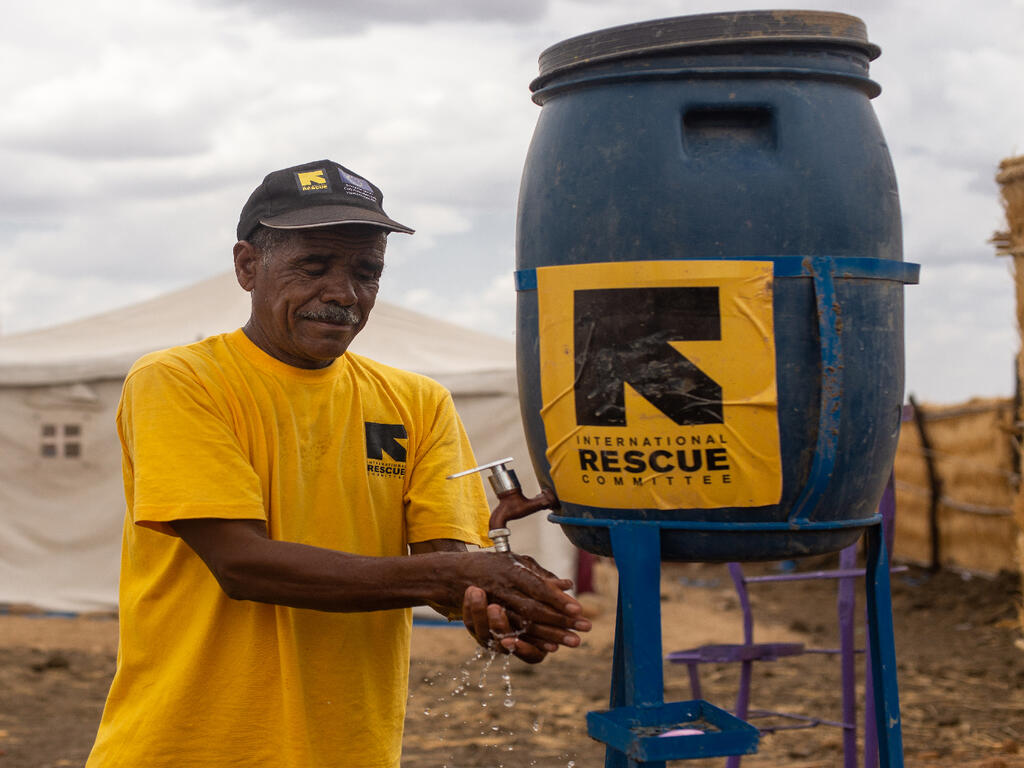 Mohammed Al Tayib, an IRC health worker, is using the IRC Covid-19 prevention hygiene facilities in a health center in Tunaydbah Refugee camp, East Sudan.