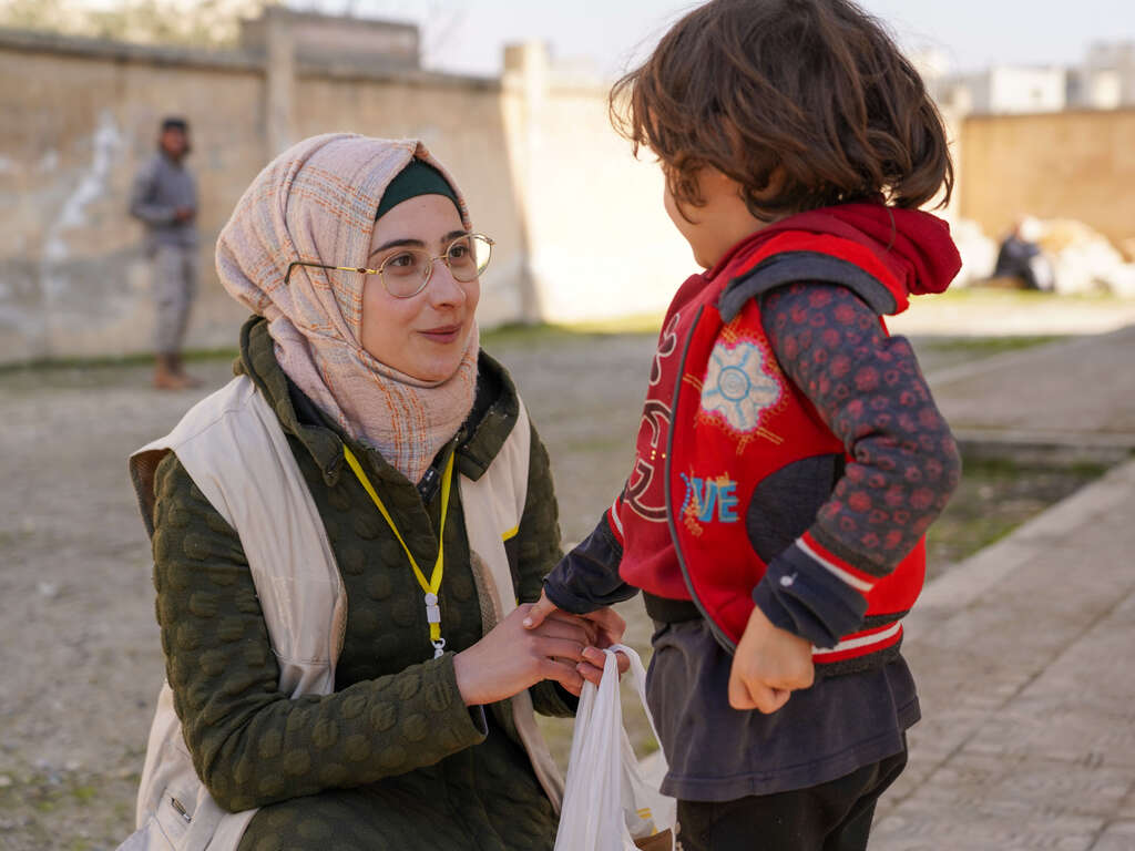 IRC staff member speaks with child. The International Rescue Committee is working rapidly to assist people impacted by the 6 February 2023 earthquake.