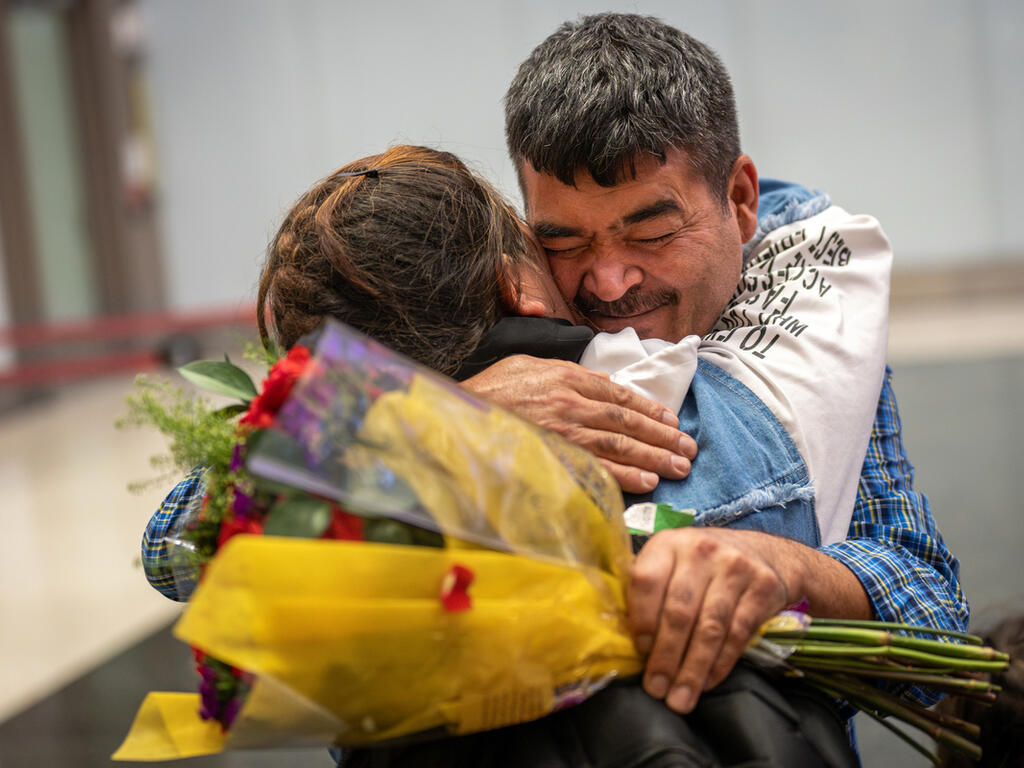 Holding flowers, Hazar Hussaini hugs his daughter Sitara Hussaini after being reunited at the Salt Lake City International Airport in Salt Lake City, Utah 
