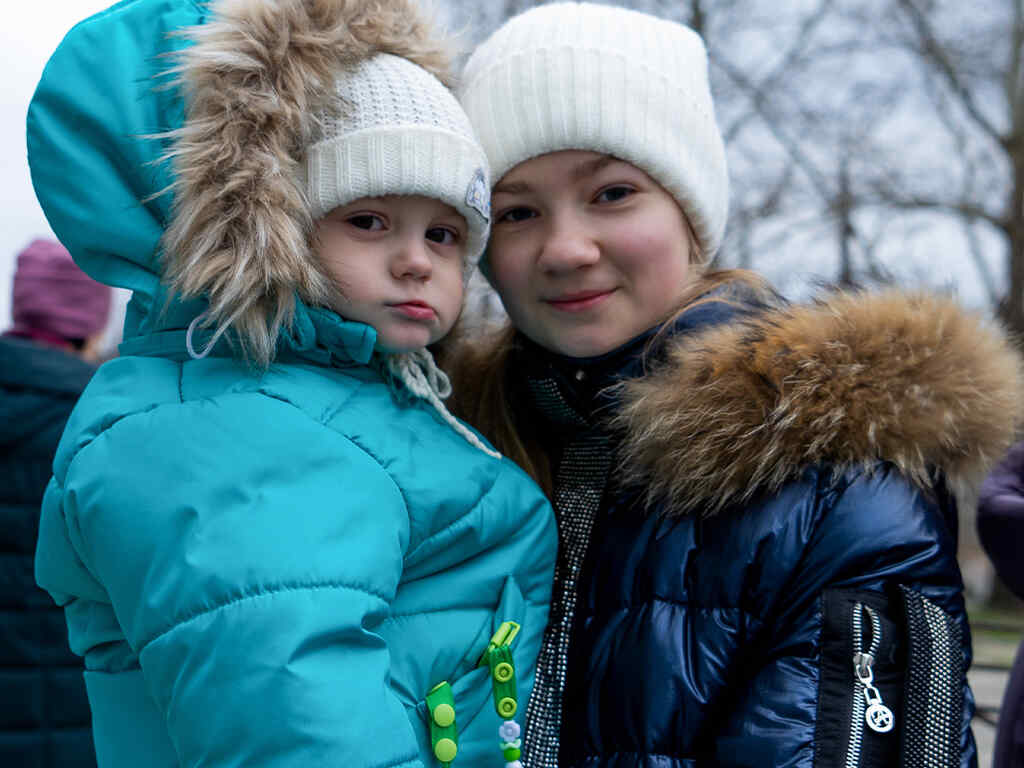 Two sisters bundled in warm clothes wait for winter supplies from the IRC in Ukraine.