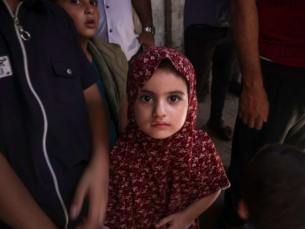 Portait of a girl wearing a head scarf. She stares solemnly into the camera.