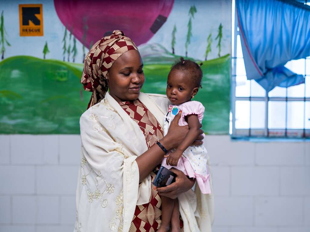A mother holds her 19-month-daughter after she is treated for signs of malnutrition at the IRC Health Facility in Maiduguri, Nigeria