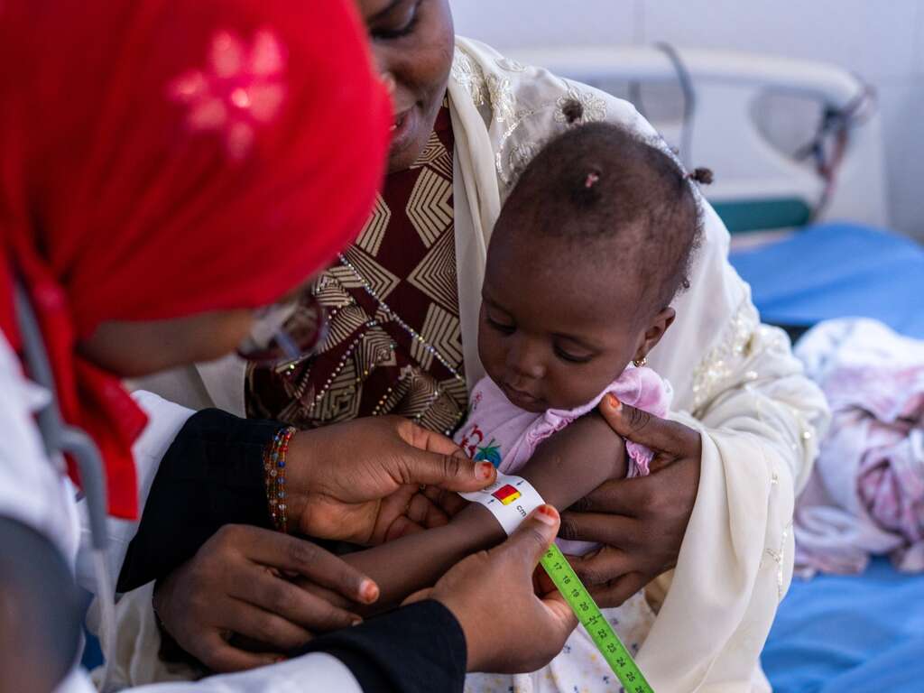 An IRC malnutrition officer screens a young child for signs of malnutrition.