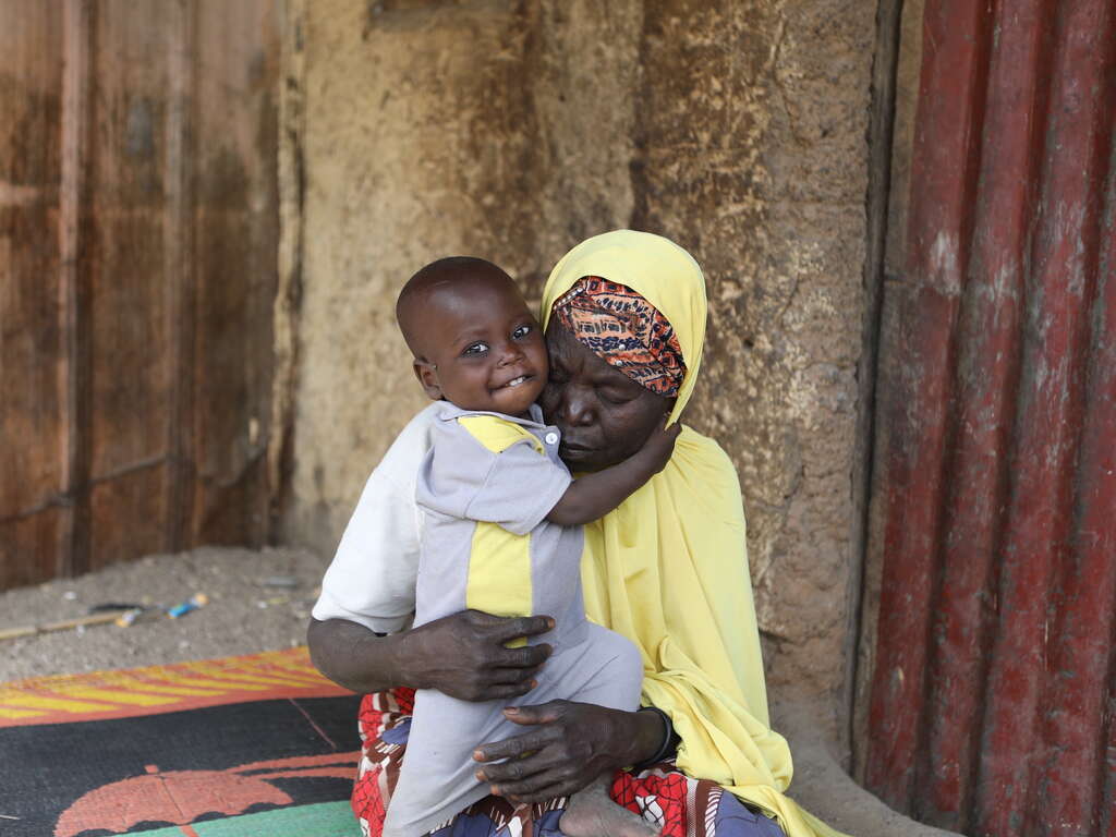 한 여성 고객이 아기를 꼭 끌어안고 있습니다. 아기는 할머니 품에서 환하게 웃고 있습니다.