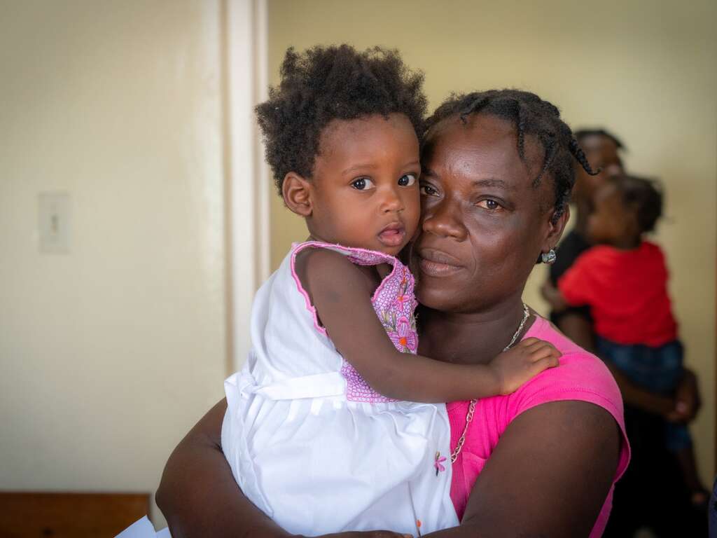 A Haitian mother holds her young daughter in her arms.