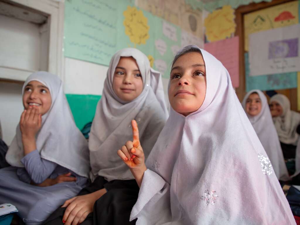 A student raises her hand to answer a question at an IRC-supported school in Afghanistan.