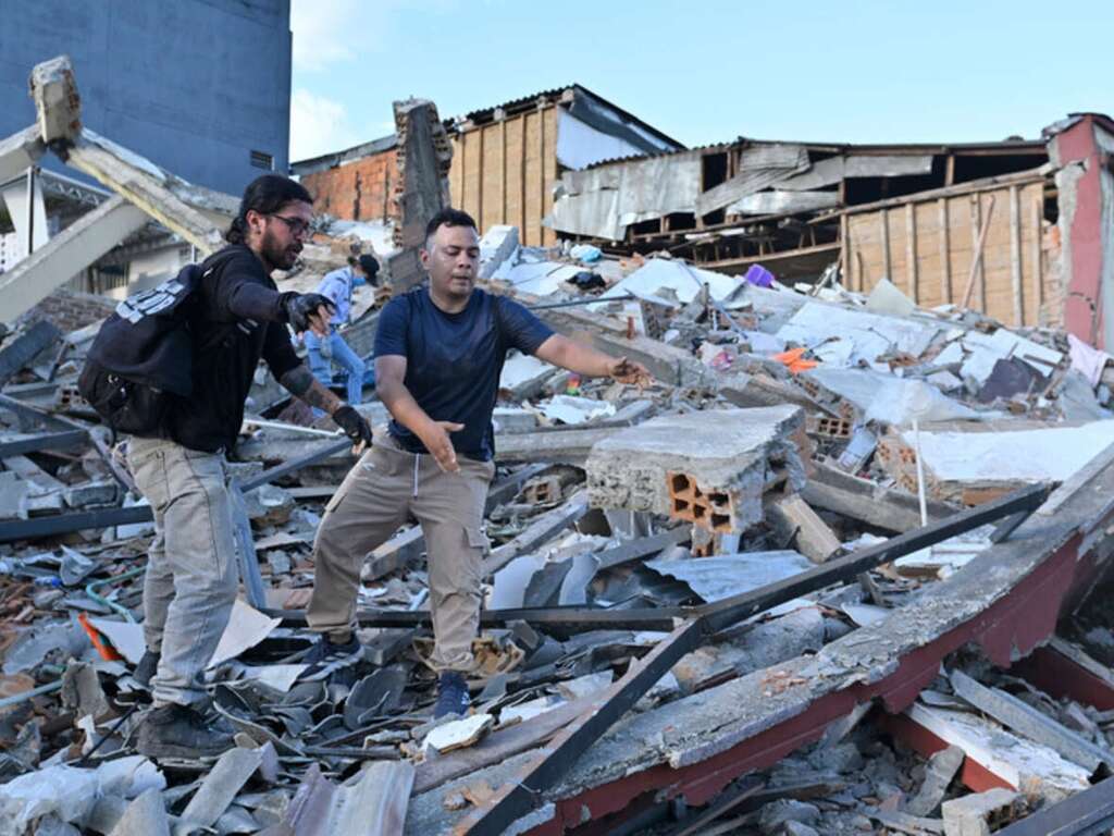 Människor och räddningsarbetare söker efter offer bland rasmassorna vid en kollapsad byggnad i stadens centrum, efter att en jordbävning med magnituden 7,4 drabbat Colombia.