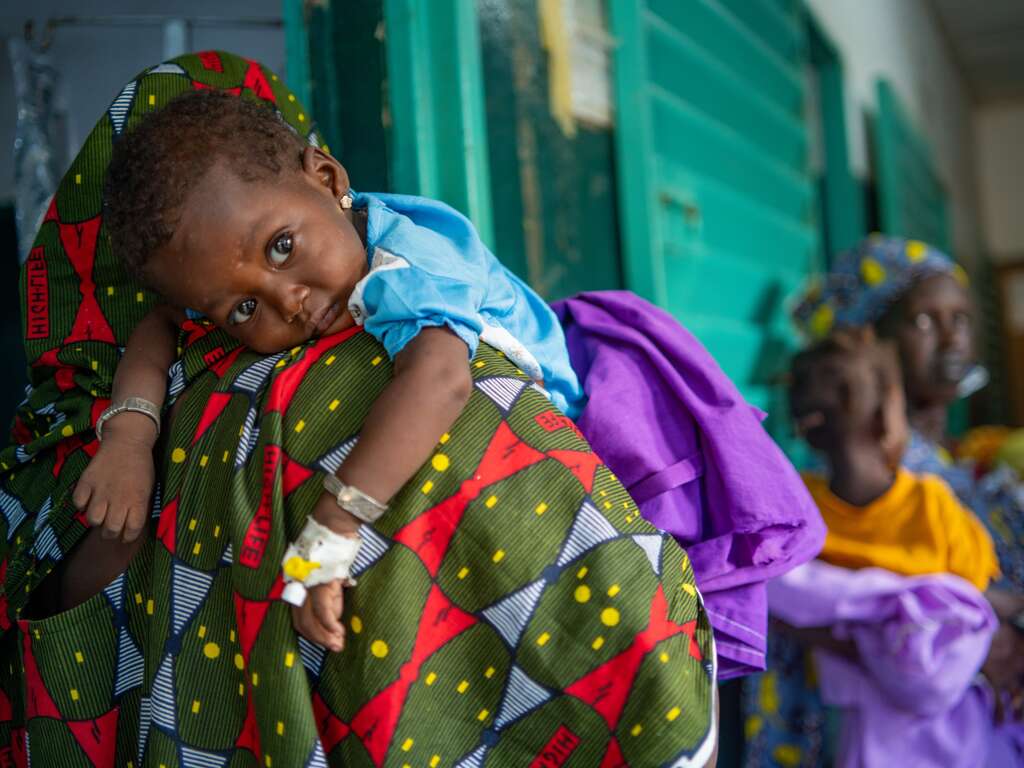 A young child hugs his mother closely.