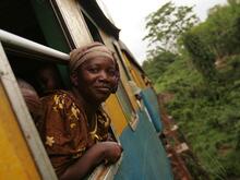 Eine Frau schaut aus einem Zugfenster und lächelt.