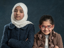 Two young girls posing for a photo with their arms crossed.