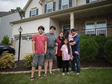 Photo of former Afghan refugee Noori standing outside his house with his family