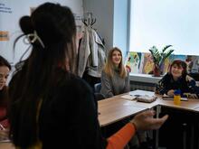 Drei Ukrainerinnen sitzen in einem Klassenraum, ihre Englischlehrerin ist mit dem Rücken zur Kamera gedreht
