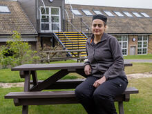 Syrian refugee Chadia sits on a school bench outside the canteen where she works