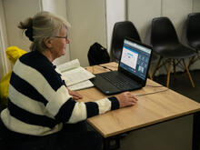 An older woman using a laptop to access the internet. 