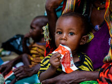 A child in Chad sits in his mother's lap and eats a RUTF bar - an effective treatment for acute malnutrition. 