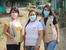 Omaira and two other IRC volunteers smiling for a photo outside of a volunteer site.