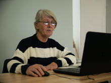A woman seated at a desk using a laptop.