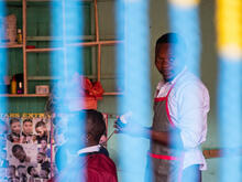 Nelson cutting the hair of a client at his barbershop in Kampala, Uganda