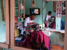 Nelson cutting the hair of a client at his barbershop in Kampala, Uganda