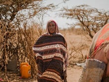 A woman poses for a photo amidst a barren landscape in Ethiopia.