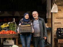 A woman and her father stand outside of their vegetable shop in Lebanon.